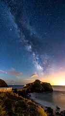 Stunning nighttime shot of the galaxy over a rocky coastline