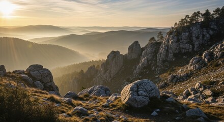 Rocky mountain terrain overlooks multiple receding ranges shrouded in morning haze bathed in golden light