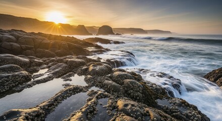 Brilliant sunburst illuminates rugged coastal rocks as ocean waves crash during twilight