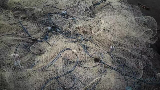 Close-up of a large pile of tangled fishing nets showcasing the intricate patterns and textures of the netting material ready for use or discarded.