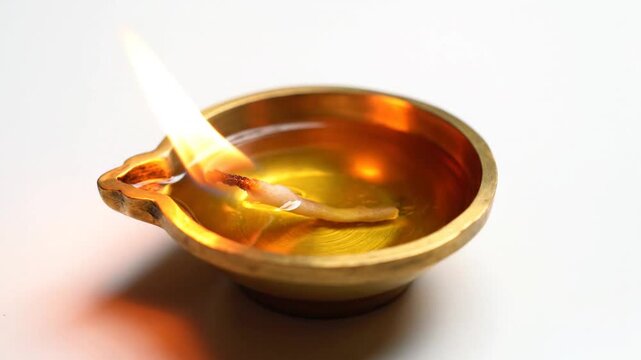 Cinematic top view of a traditional Indian clay oil lamp diya glowing with a flickering flame isolated on a clean white background during Diwali festival celebration for spiritual enlightenment.