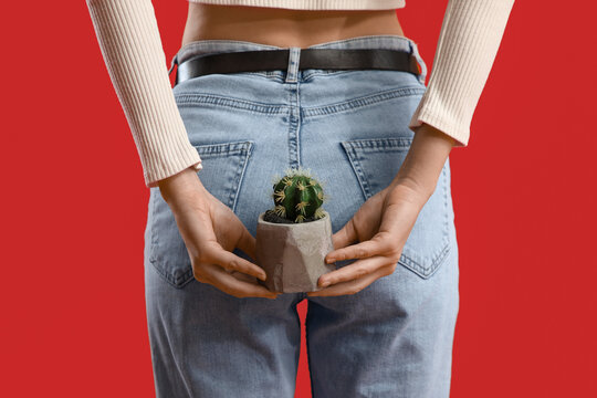 Young woman with hemorrhoids and cactus on red background, back view