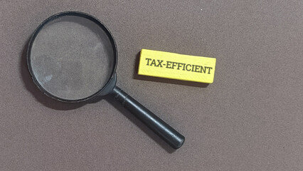 Magnifying glass over the words TAX-EFFICIENT, symbolizing the careful examination and analysis...