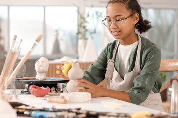Teenage African-American sculptor with walker polishing vase in workshop