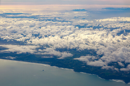 An aerial view of part of New Zealand, also known as Aotearoa, "The Land of the Long White Cloud." At the bottom is Muriwai Beach, with the Hauraki Gulf in the background