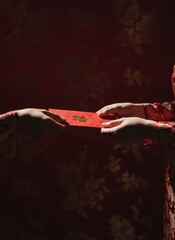 close-up lifestyle photo, red envelope being passed, natural skin tones, emotional moment, dark red background