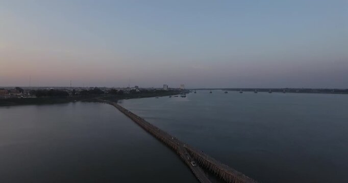 Aerial view descending to reveal the Koh Paen bamboo bridge at dusk in Kampong Cham.