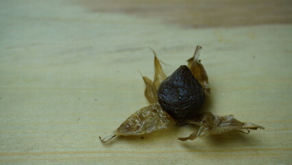 Pile of Single Clove Black Garlic, Allium sativum on Wood Background