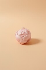 Pink flower shaped object sits on a tan background
