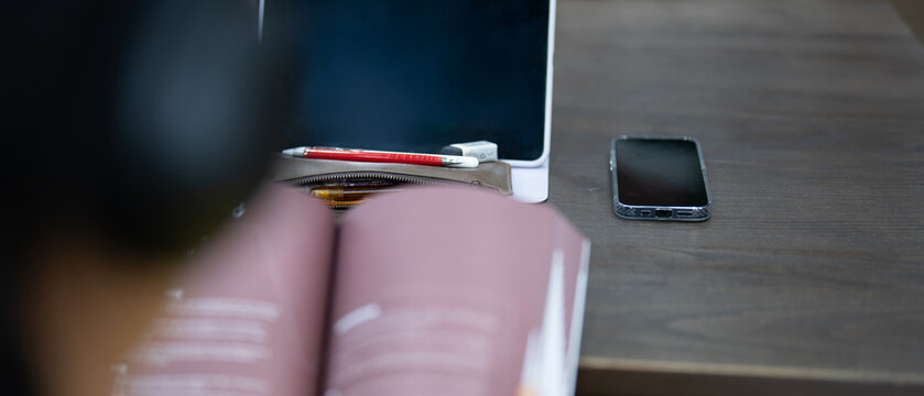Asian student taking notes in notebook and using tablet for e-learning - Powered by Adobe