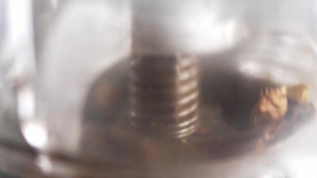 Interior view of a motorized coffee burr grinder in action. Close up