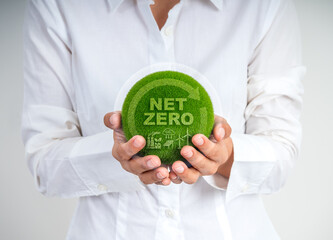 A person holding a green grass-covered globe with &ldquo;Net Zero&rdquo; text, symbolizing carbon neutrality, clean energy, and environmental sustainability. Ideal for eco, climate change, and ESG concepts.