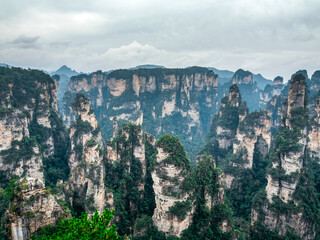 Stunning landscape of Zhangjiajie sandstone pillars covered with lush greenery under cloudy sky. This iconic scene inspired the floating mountains in the movie. Ideal for travel and nature themes. © tete_escape