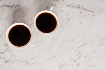 Two cups of black coffee on a light background
