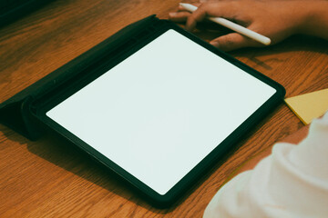 A businessman using digital tablet with blank white screen at wooden desk, productive work from home and remote office mockup concept.