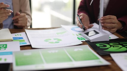 Businesswoman discussing ESG policies and renewable wind energy. Two businesswomen meeting to plan a clean energy project. They are analyzing charts and documents related to ESG and sustainability. - Powered by Adobe