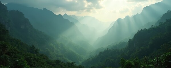 Scenic landscape photo of mountains covered in lush green forests and jungles. The image shows sun rays breaking through clouds creating a serene view of nature.