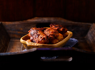 Fried chicken wings with potatoes on a rustic background. Soft focus.