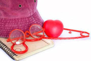 Red heart, red hat, red coat hanger, and notebook arranged neatly, isolated on clean white background.