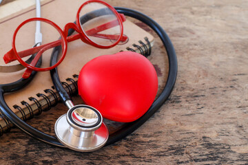 Medical equipment stethoscope forming heart shape, red heart. Place it on the old wooden floor.