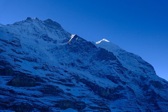 Close-up of the Eiger North Face in the Swiss Alps, cold blue shadows and rugged rock textures
