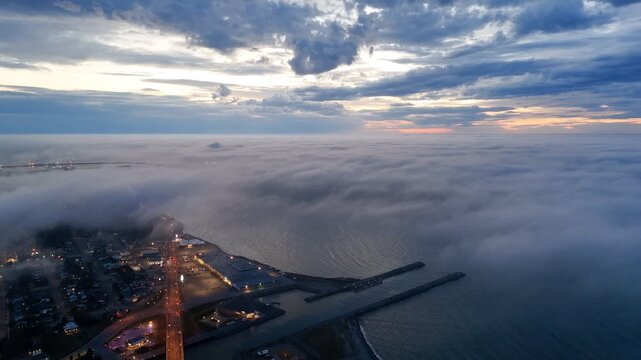 Aerial view of Matane city at dusk with river, fog, low clouds and city lights along St Lawrence River, Quebec, Canada. g.
