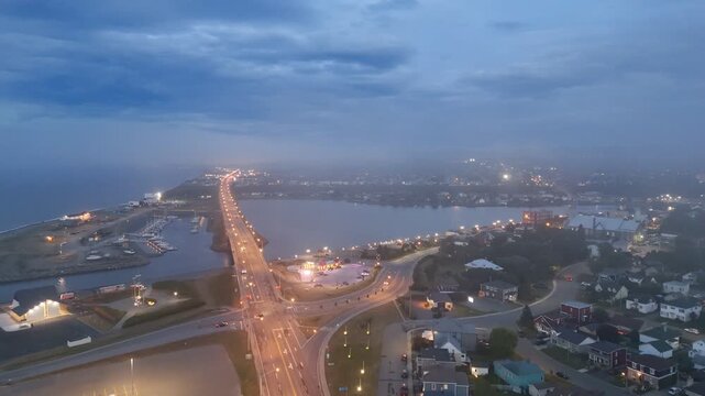Aerial view of Matane city at dusk with river, fog, low clouds and city lights along St Lawrence River, Quebec, Canada. g.