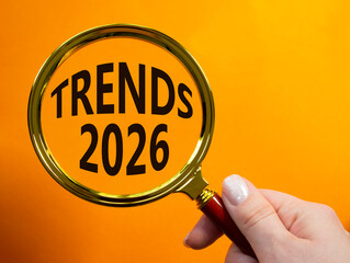 Trends 2026 symbol. Magnifying Glass with words Trends 2026. Businessman hand. Beautiful orange background. Business and Trends 2026 concept. Copy space.