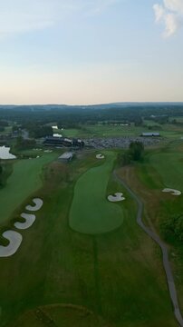 Drone glides above fairway and bunkers toward the clubhouse at TPC Toronto at Osprey Valley in Alton, Caledon, Ontario, Canada during soft evening light.