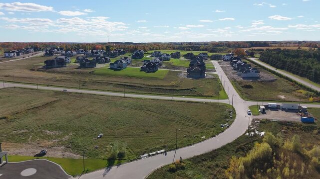 Drone aerial over an Alton, Caledon (Ontario) subdivision with a cul-de-sac, open lots, and newly built houses under a clear autumn sky&mdash;showing suburban growth.