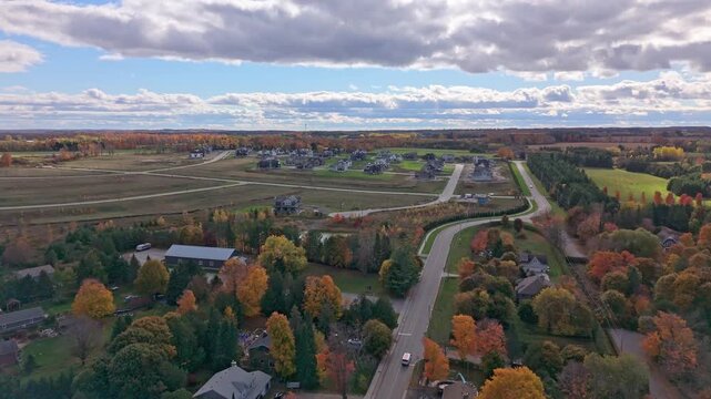 Aerial drone shot of new housing development near Alton, Caledon, Ontario, with curving roads, autumn trees, and dramatic clouds&mdash;showing suburban expansion.