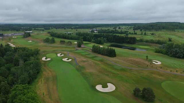 Drone aerial over TPC Toronto at Osprey Valley with winding fairways, bunkers and ponds under dramatic overcast skies in Alton, Caledon, Ontario, Canada.