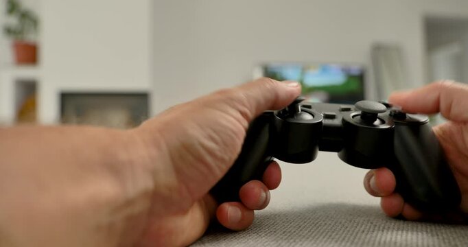 Close-up of hands holding video game controller in modern living room