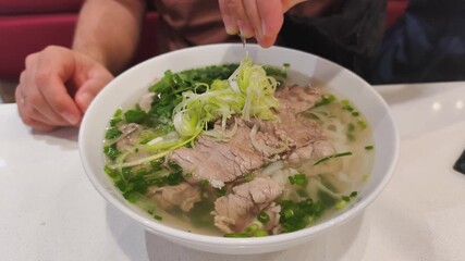 Fresh herbs in Lean Pho Bo make taste very light. Every Lean Pho Bo with sliced meat is low fat meal. Tasty Lean Pho Bo on wooden table is authentic asian food for healthy lunch in restaurant.