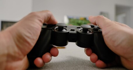 Close-up of hands holding video game controller in modern living room  - Powered by Adobe