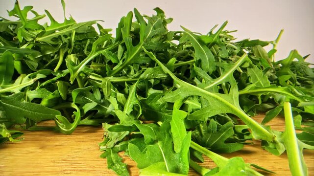Leafy Green Vegetable With Fresh Arugula Over A Wooden Table. Tracking Shot