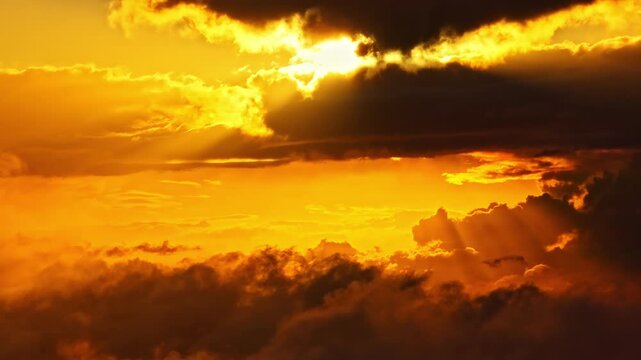 Golden sunbeams break through heavy clouds above a glowing horizon, casting dramatic light across the upper atmosphere during a calm aerial sunset.