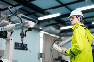 Engineer inspecting industrial robotic arm in smart factory, highlighting automation technology, robotics maintenance, safety protocols and teamwork in modern manufacturing environments.
