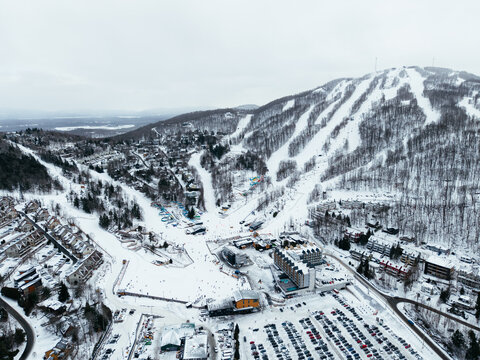 Aerial winter view of Bromont ski resort with snowy slopes, village and parking area in Quebec, Canada. g.
