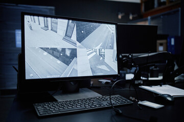 Naklejka premium Computer monitor displaying multiple security camera feeds showing empty urban streets, keyboard and mouse placed on desk, surveillance equipment used for monitoring public areas