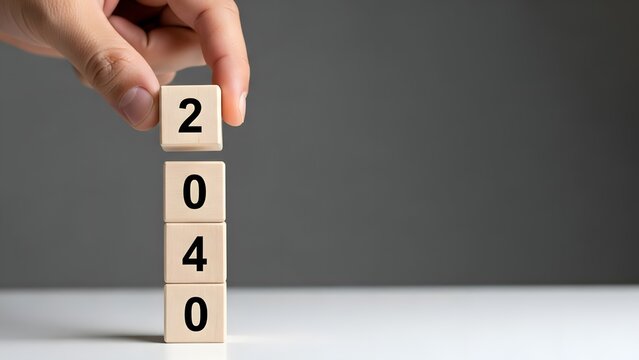 Hand placing wooden blocks to form the year 2040 against a plain gray background