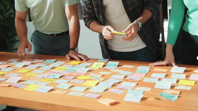 Close up of manager writing idea on sticky note and explain idea about web design. Professional marketing team or programmer brainstorming idea while looking at tablet with color palette. Symposium.