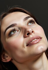Close-up portrait of a person gazing upwards with soft lighting, detailed skin texture, natural beauty, and a serene expression against a dark background