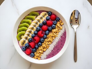 Healthy Smoothie Bowl Topped with Fresh Kiwi, Banana, Blueberries, Raspberries, Granola, and Chia Seeds on a White Marble Table for a Nutritious Breakfast