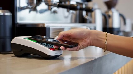 Woman making contactless payment at a coffee shop counter.