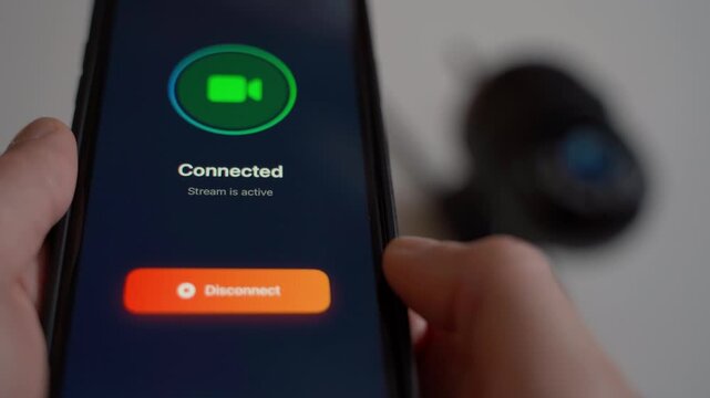 On the mobile app, the user connects to a surveillance camera in the background, close-up