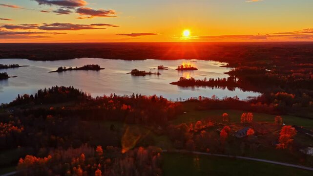 Aerial sunset view over inesu lake as sun rays reflect across water and autumn forest shoreline