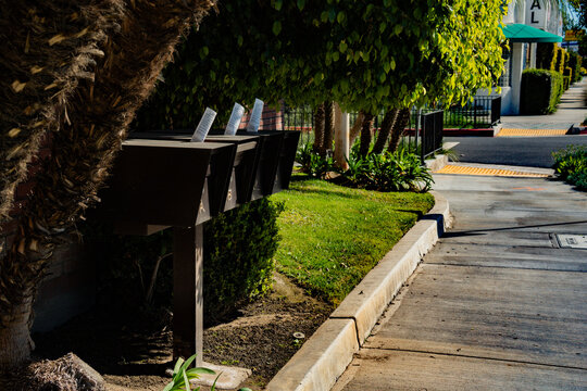 Row of mailboxes with letters sticking out on a sunny suburban street