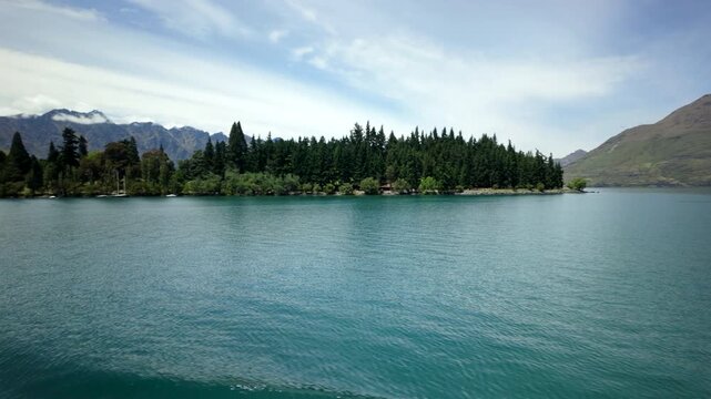 Calm turquoise lake with pine peninsula and mountain slope