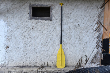 Yellow and black raft paddle, a durable single-bladed manual tool used for steering and propelling inflatable rafts and canoes in whitewater or flat water conditions